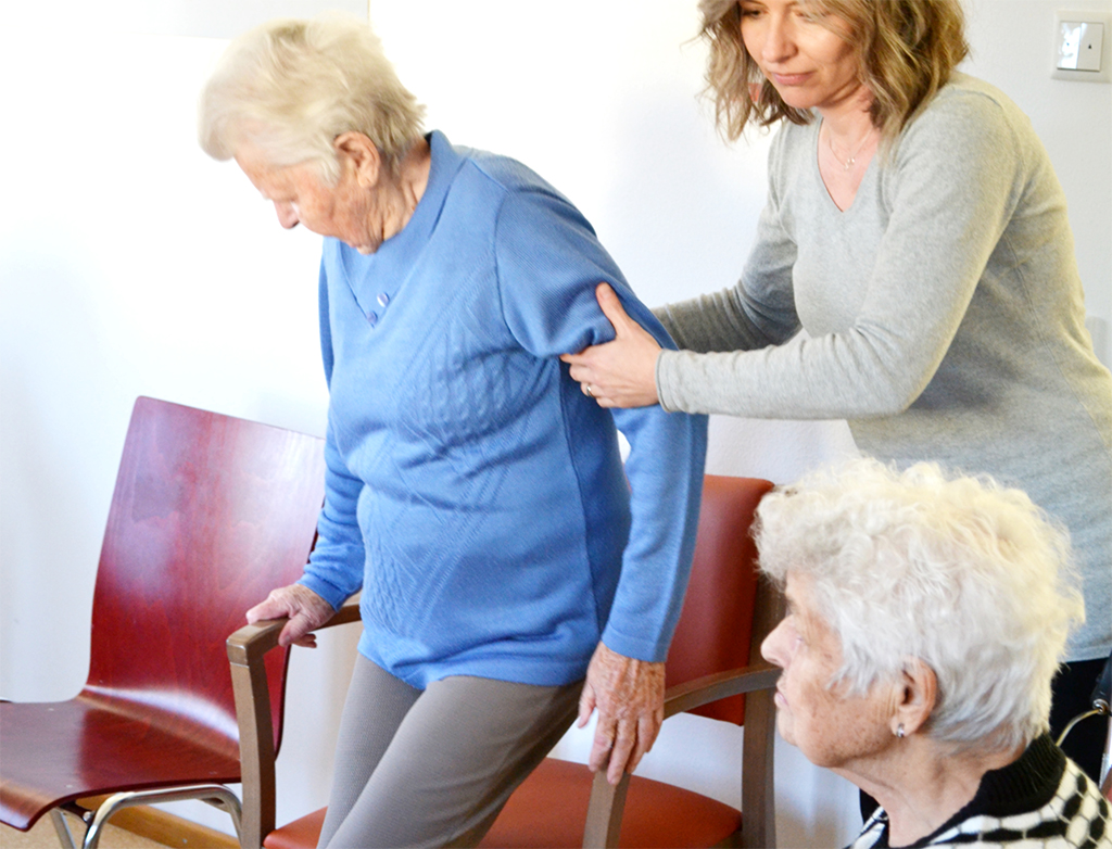 Pflegekraft unterstützt Seniorin
